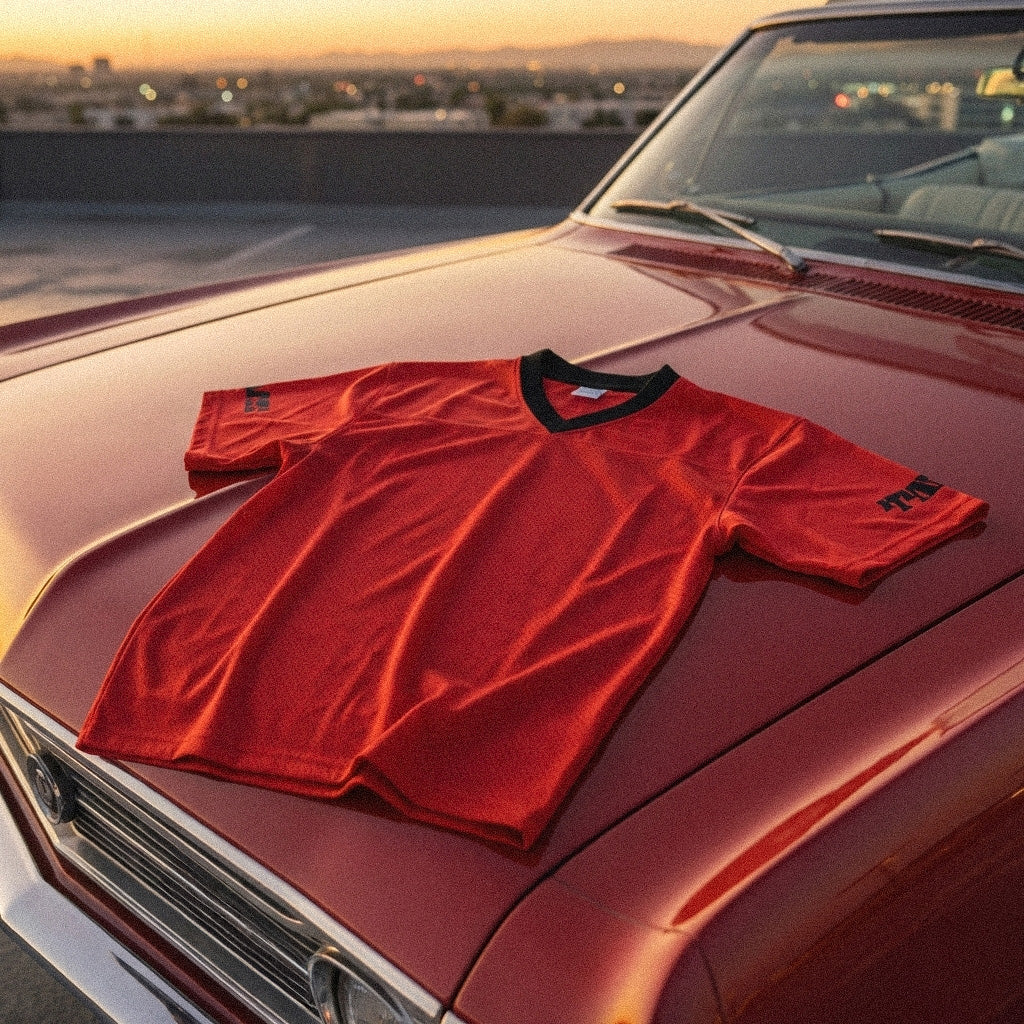 Red t-shirt on a classic car with a cityscape in the background